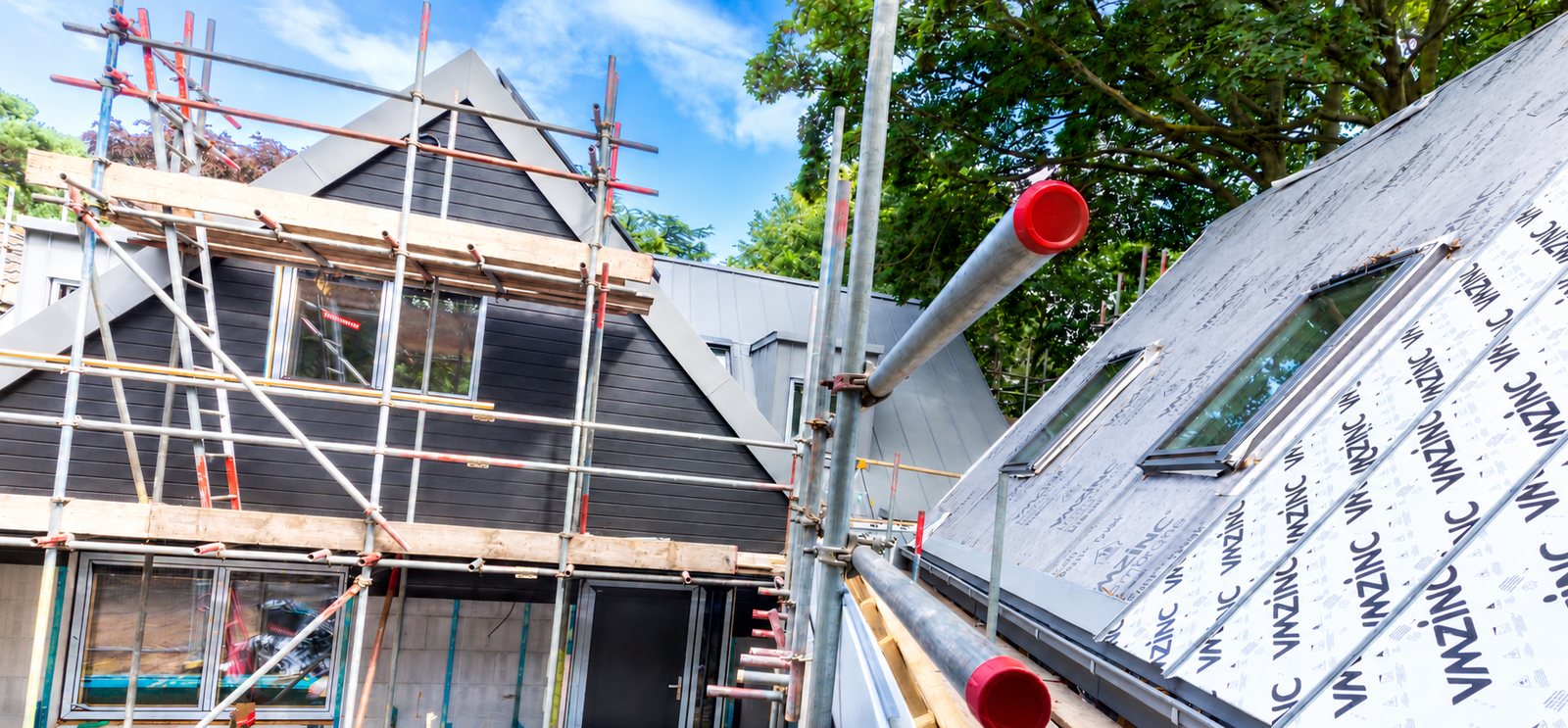Hybrid ICF and SIPs home under construction with cladding, rooflights and zinc roofing going on together