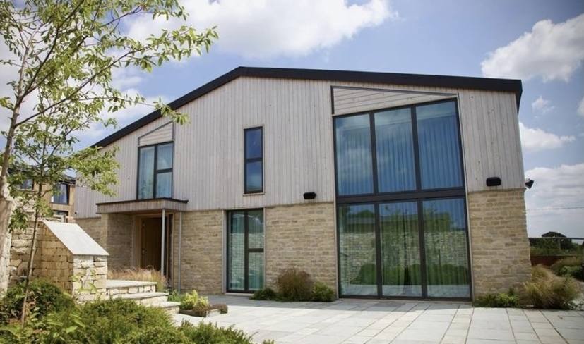 Low energy home with stone plinth and timber cladding