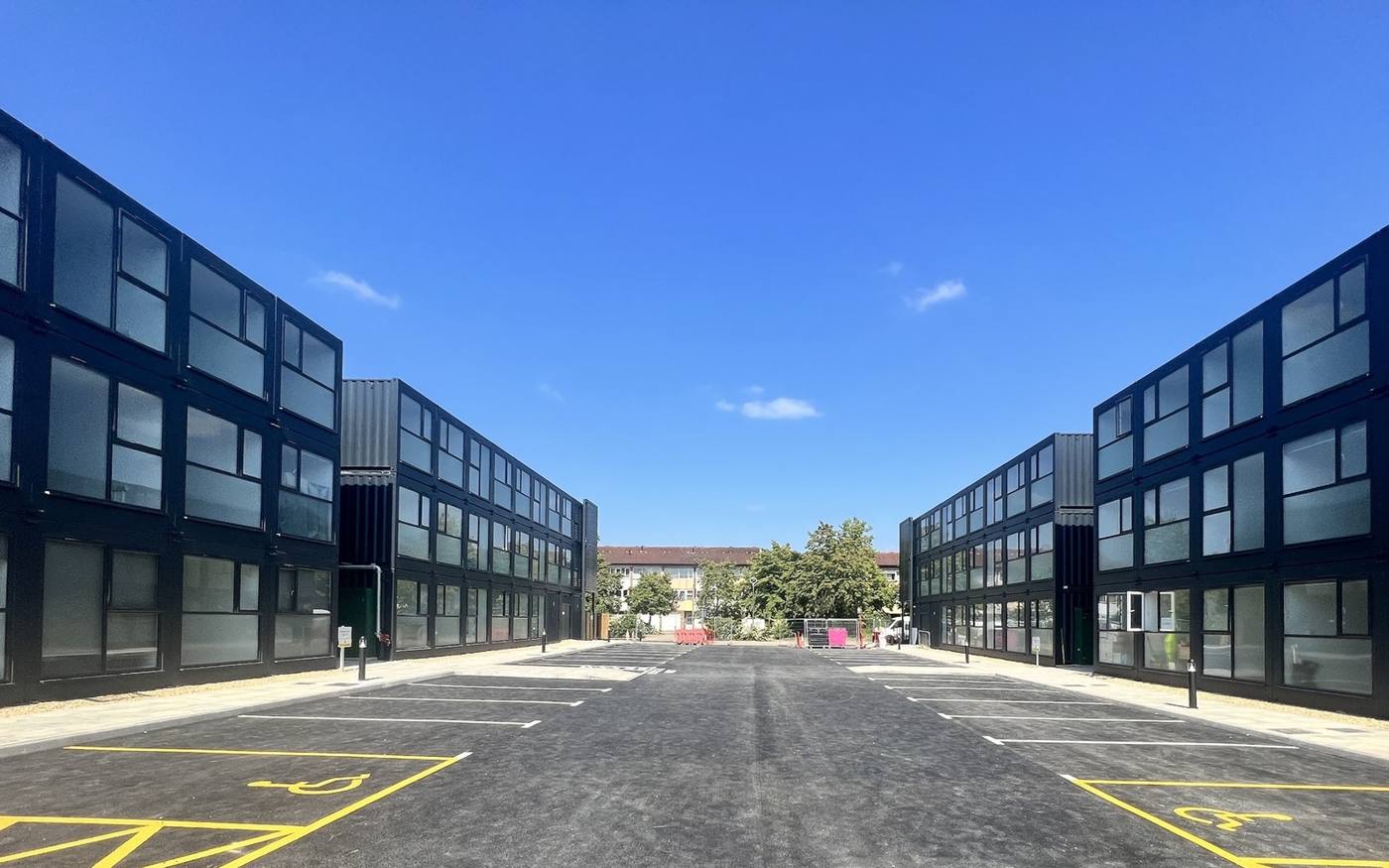 Two rows of stacked modular apartment blocks either side of a car park