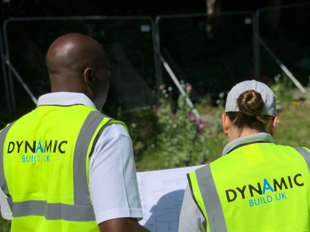 Two Dynamic Build UK team members in branded hi-vis reviewing drawings on site